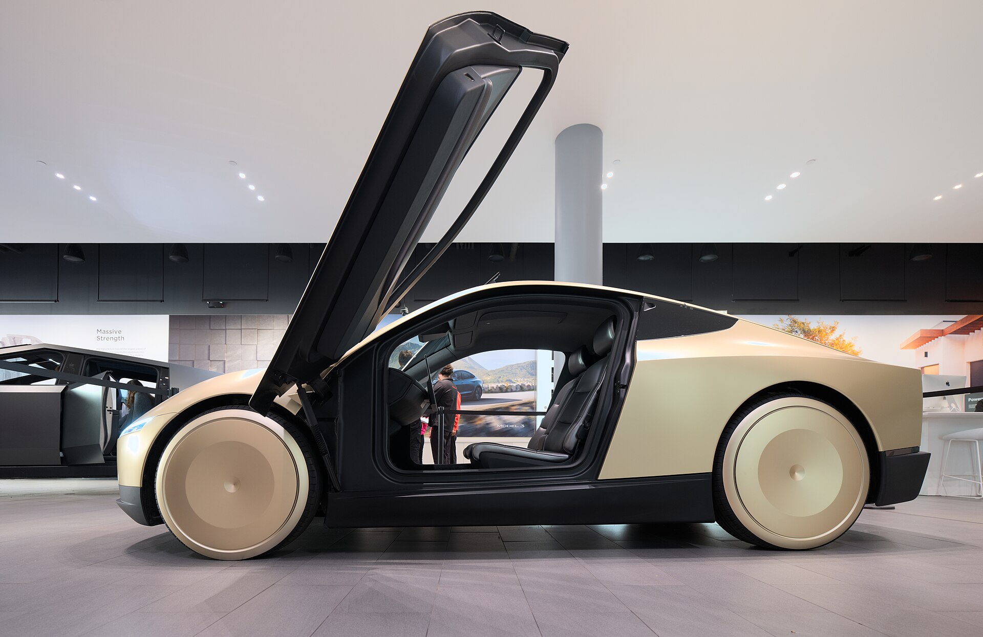 A Tesla Cybercab, the company's dedicated robotaxi, on display with its door open.
