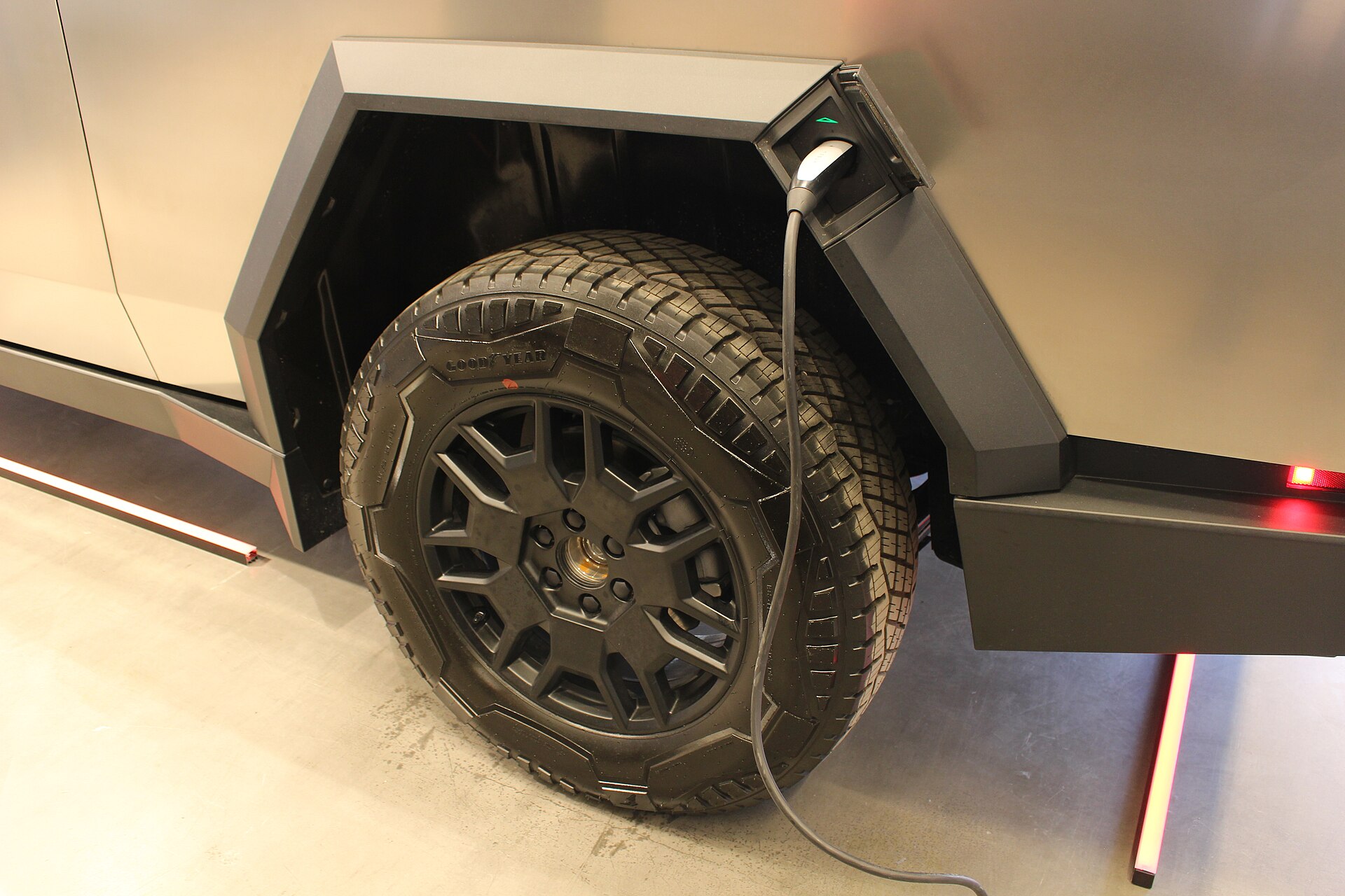 A Tesla Cybertruck charging through a NACS connector at a charging station.