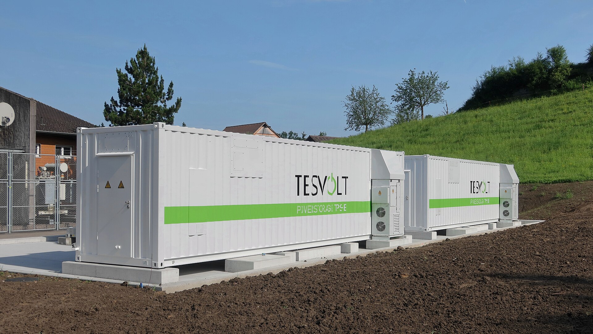 A Tesvolt community-scale battery energy storage system installed beside homes in a residential area.