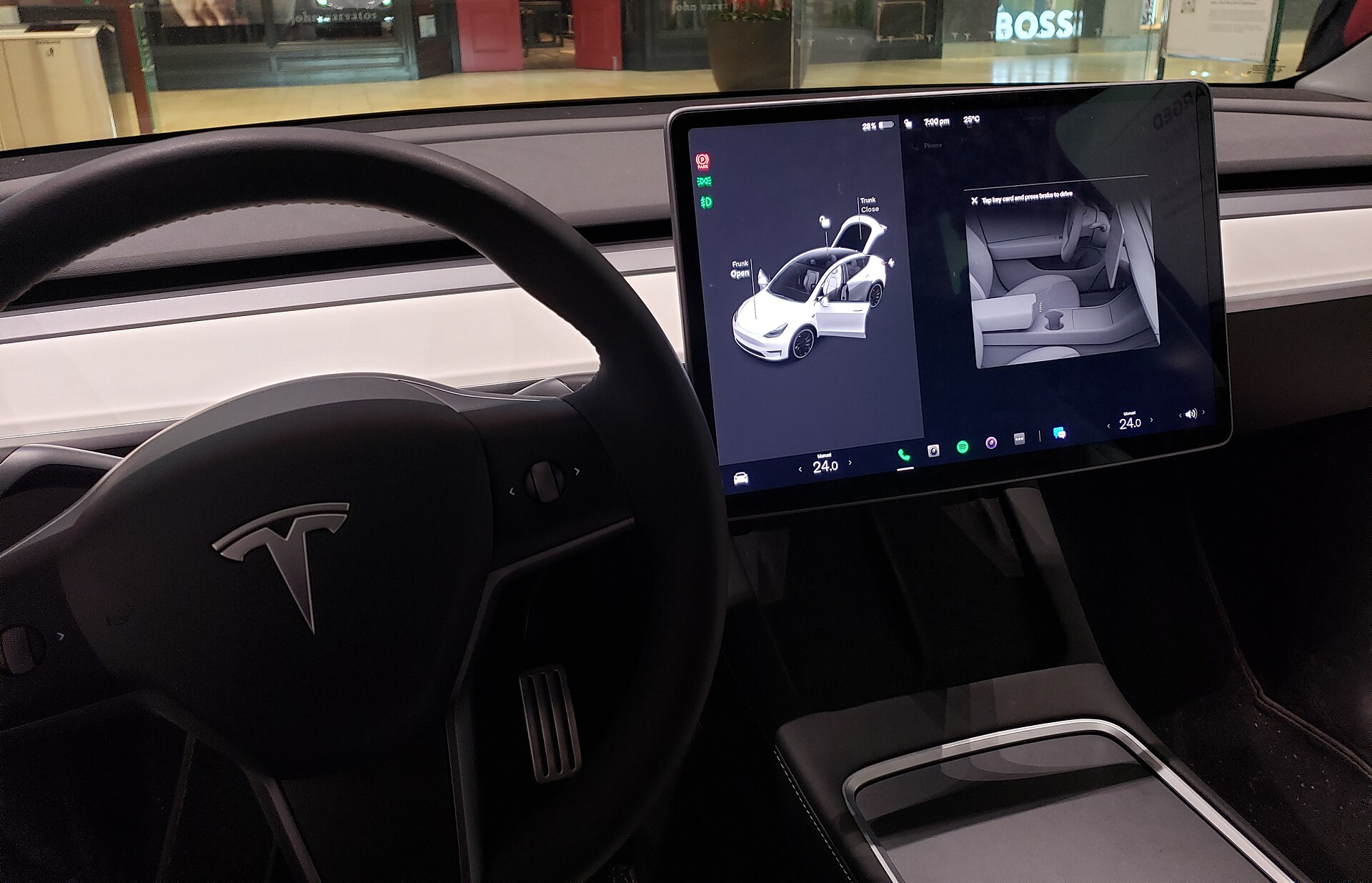 A Tesla Model 3 steering wheel and central touchscreen, the display where Full Self-Driving information appears.