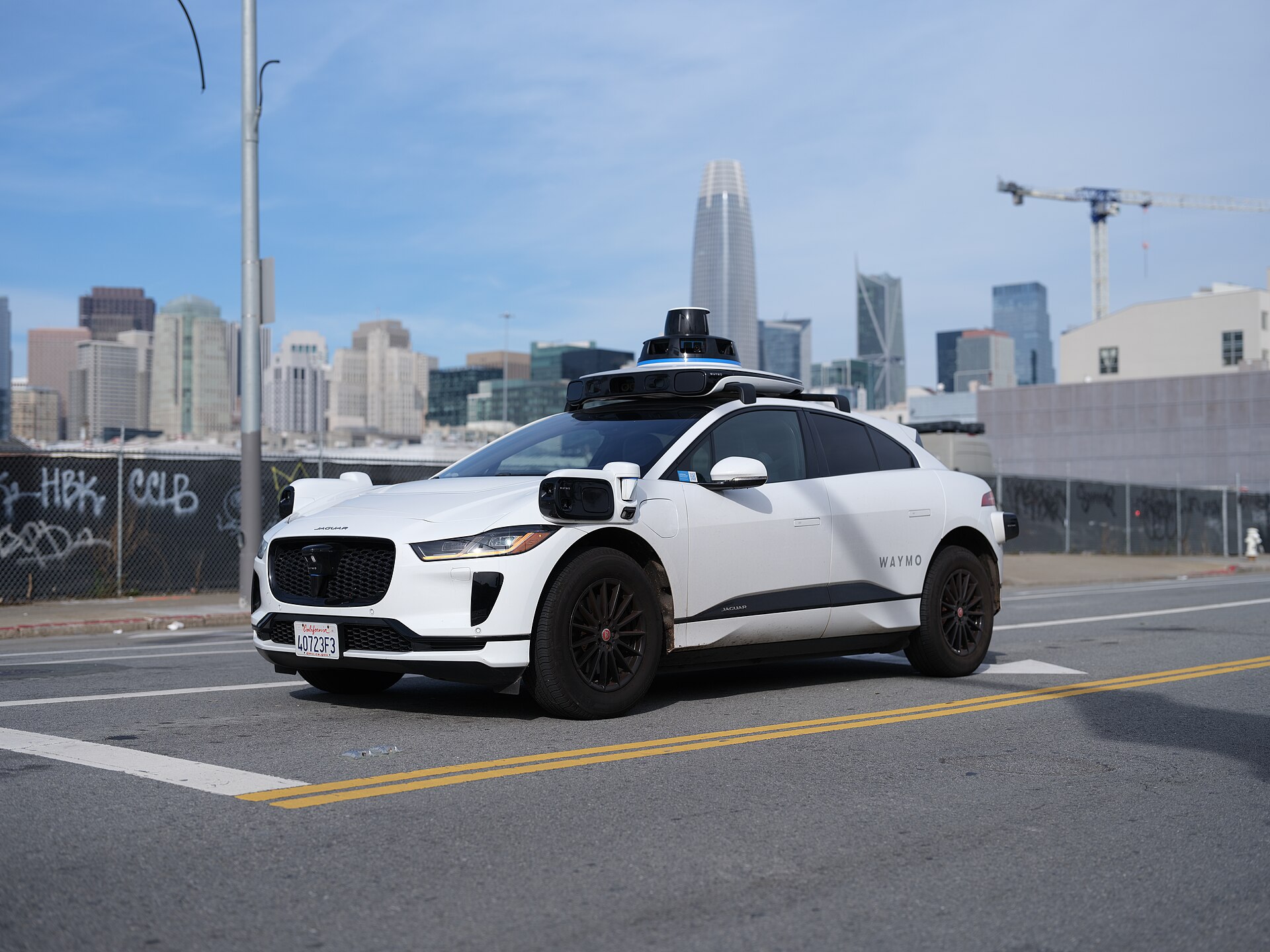 A Waymo-operated Jaguar I-Pace robotaxi on a San Francisco street, running with no person in the driver seat.